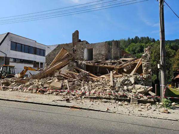 Bager JCB 3CX pri búraní obvodového muriva domu v Dolnom Kubíne