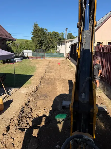 Prípojky elektriny, vody a kanalizácie + prístupová cesta, Istebné 1 Bager JCB 3CX pri výkope ryhy pre prípojky na pozemku v Istebnom